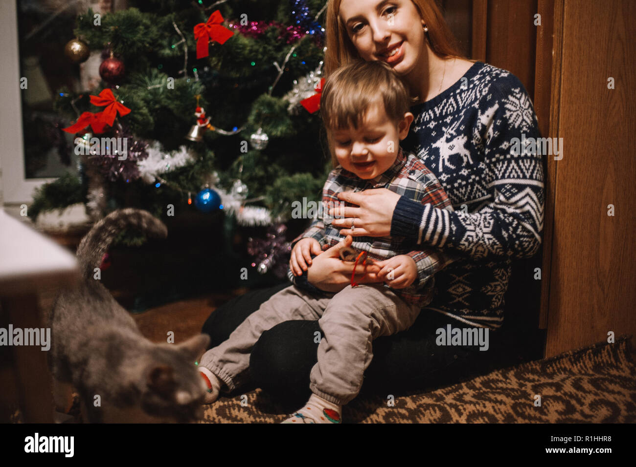 Happy mother and son sitting beside Christmas tree at home during Christmas holidays Stock Photo