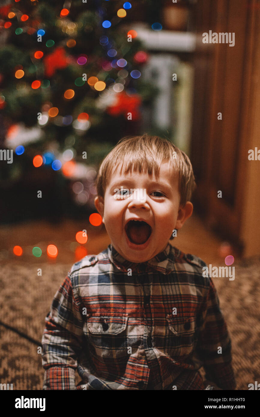 Cheerful baby boy with mouth open playing at home during Christmas holidays Stock Photo