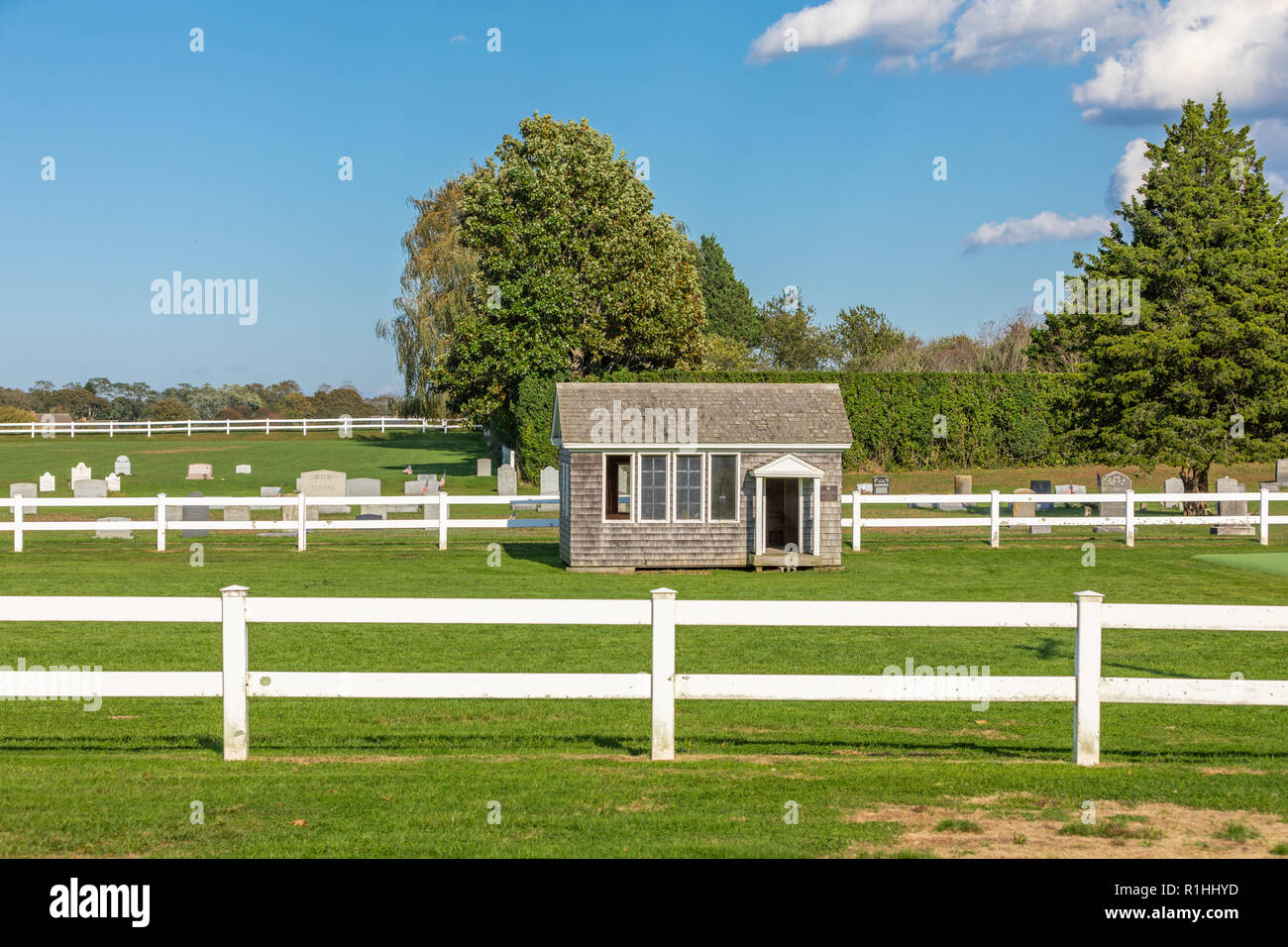 small house in a green lawn with a cemetery in the background Stock Photo