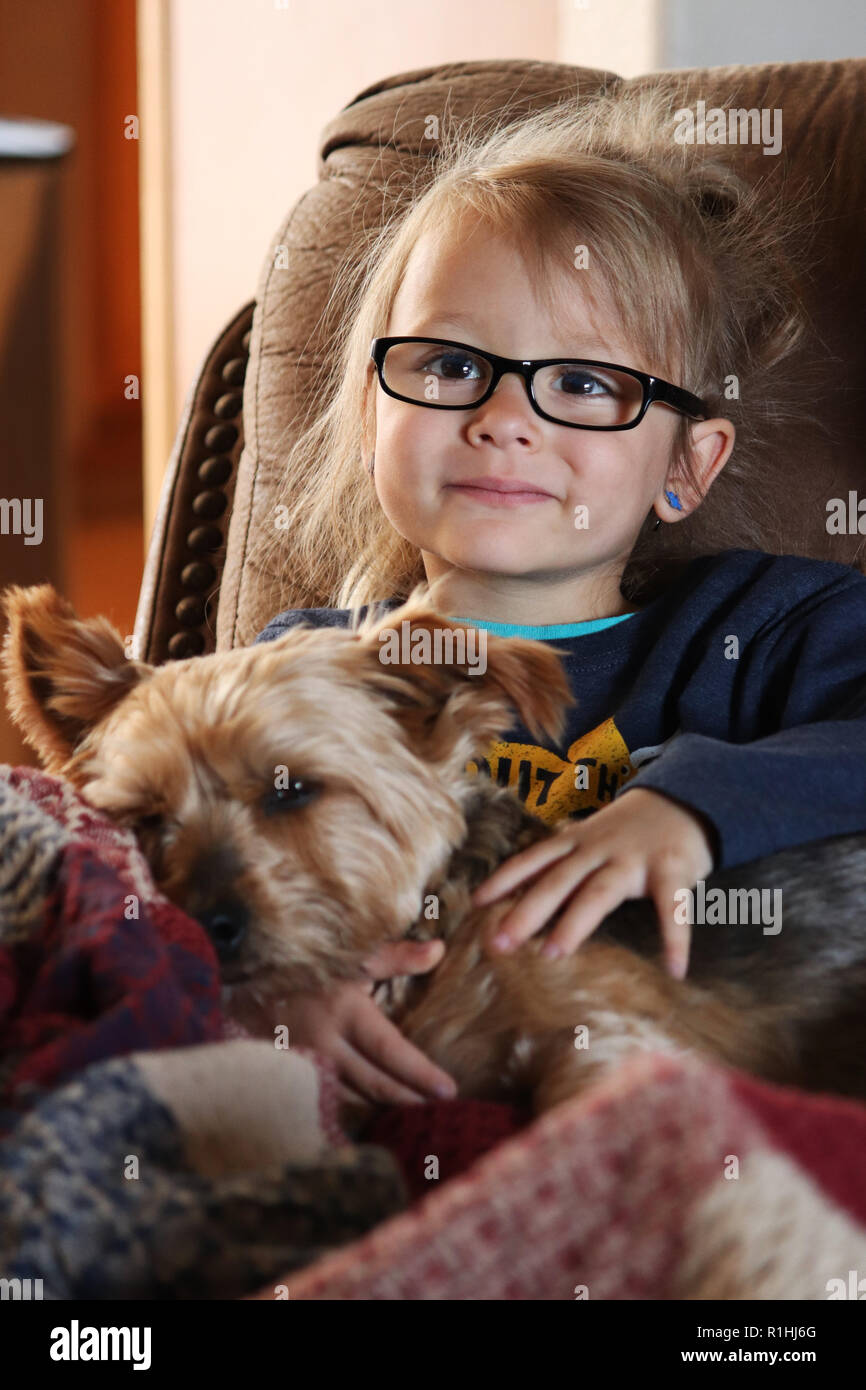 Child relaxing on the sofa with its best friend Stock Photo
