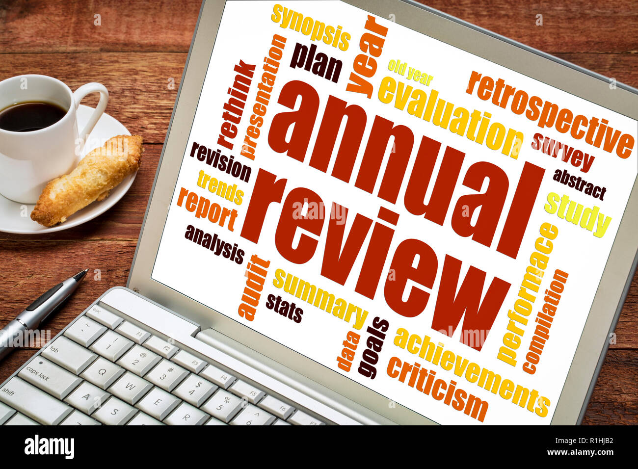 annual review word cloud on a laptop screen with a cup of coffee Stock Photo