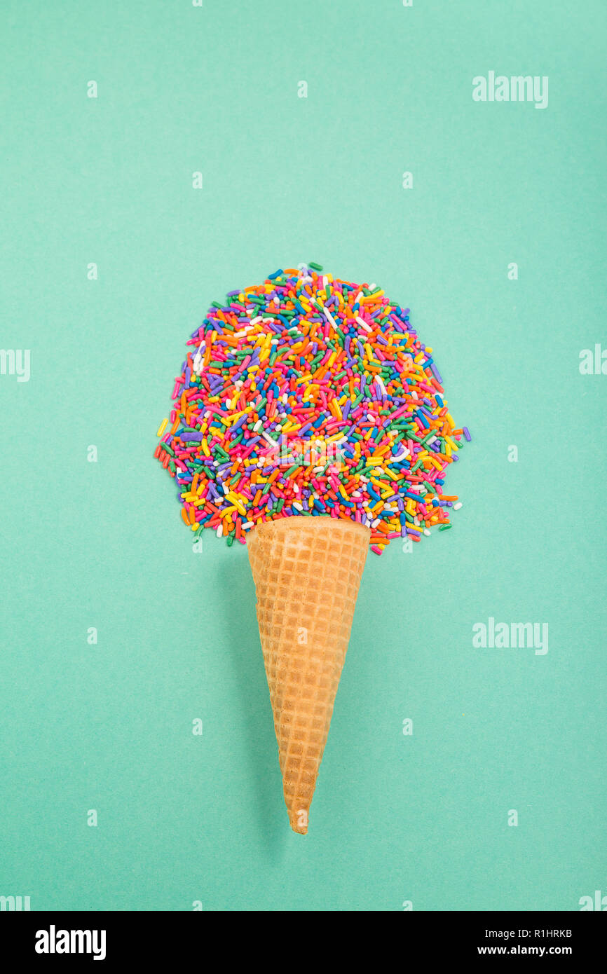 Ice cream cone with sprinkles in the shape of a scoop on a pale green background Stock Photo