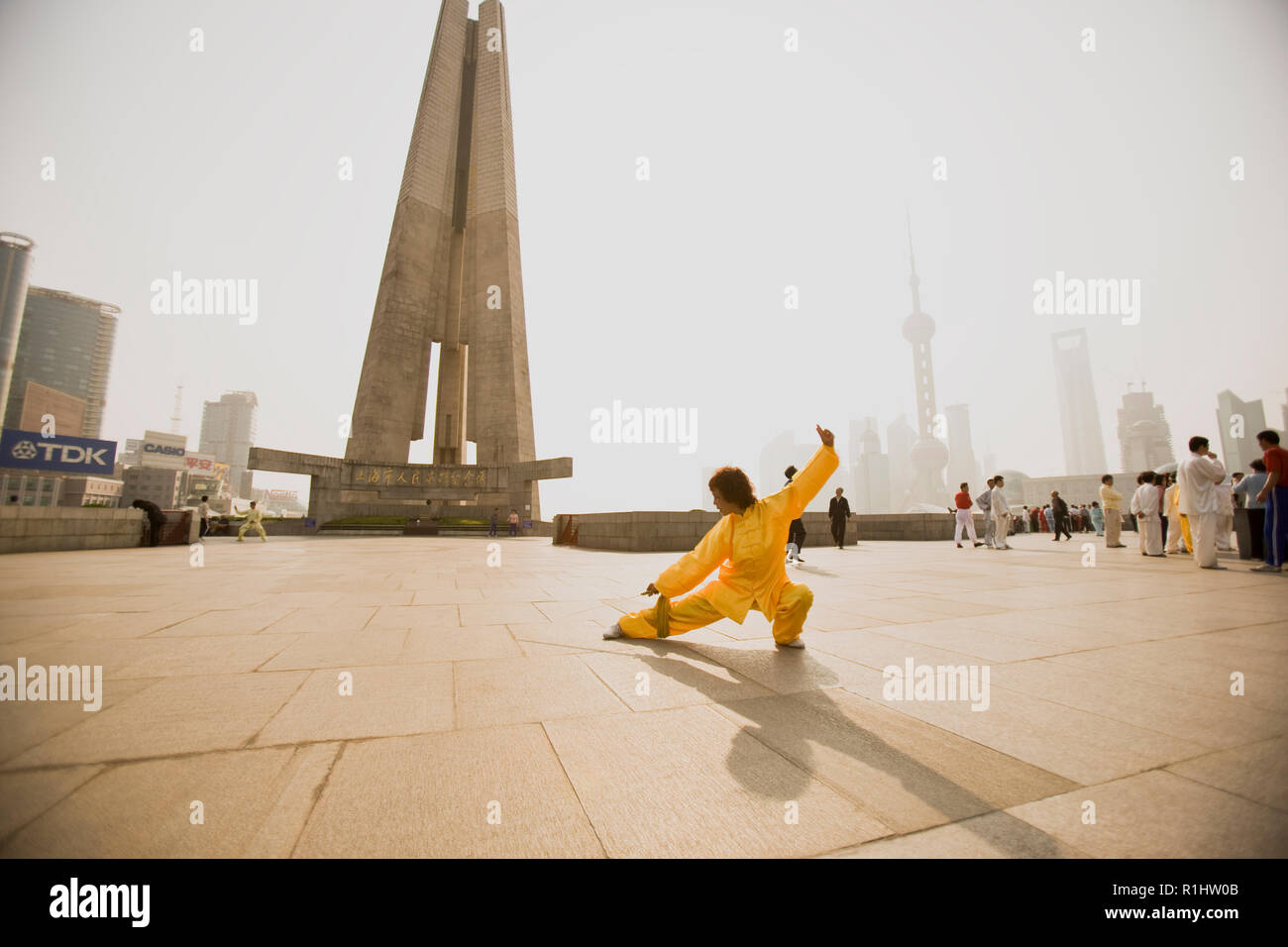 Woman in traditional clothing practicing martial arts in a city square in the sunshine Stock