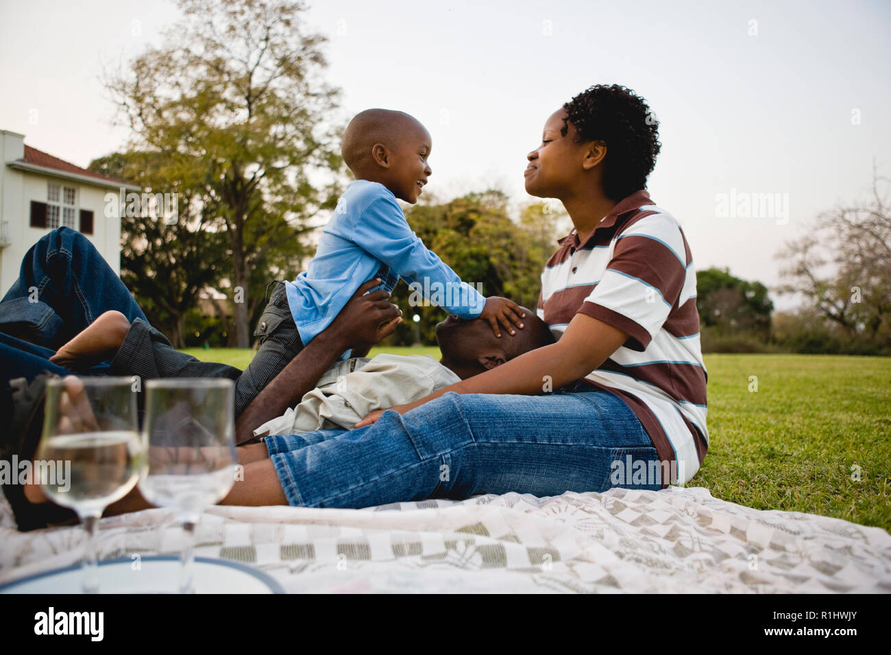 Mid-adult couple sitting having a picnic with their toddler son. Stock Photo