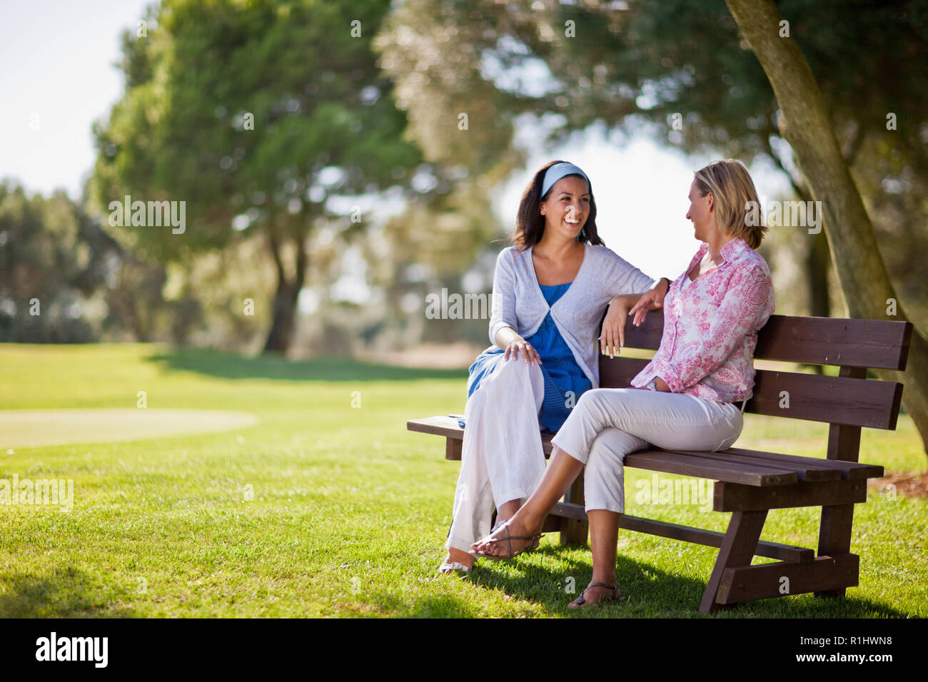Happy friends talking together in a serene green park. Stock Photo