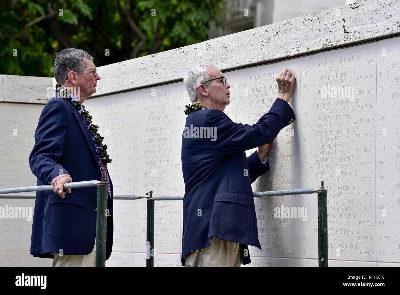 U.S. Army Col. (Ret.) Charles H. McDaniel Jr., watches his brother, Larry McDaniel, place a rosette next to their father's name, U.S. Army Master Sgt. Charles H. McDaniel Sr., at the National Memorial Cemetery of the Pacific, Honolulu, Hawaii, Sept. 21, 2018. McDaniel Sr., was recently identified by the Defense POW/MIA Accounting Agency after his remains were returned during a unilateral transfer from the Democratic People’s Republic of Korea. Stock Photo
