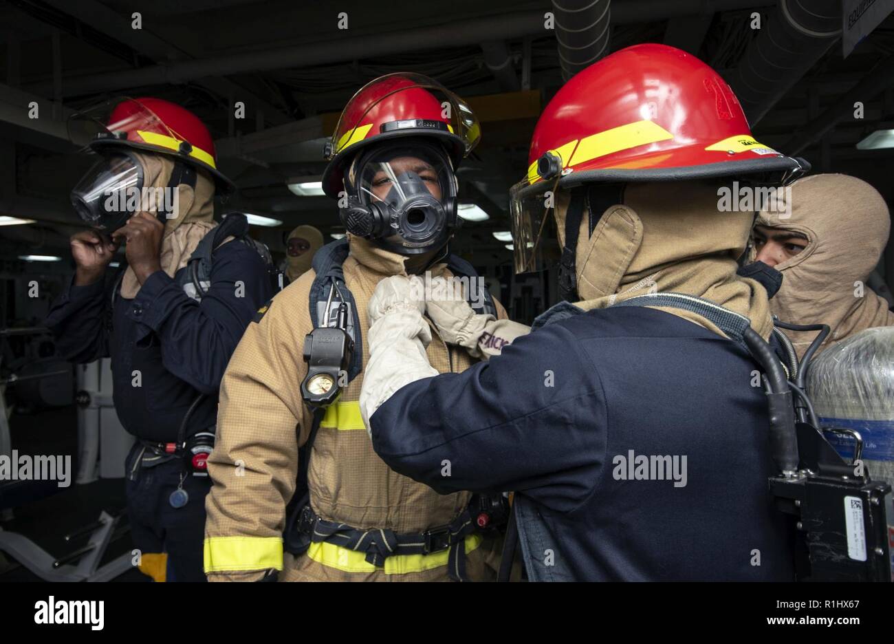 PACIFIC OCEAN (Sept. 21, 2018) Sailors, assigned to the amphibious assault ship USS Bonhomme Richard (LHD 6), don firefighting ensembles during a general quarters drill. Bonhomme Richard is currently underway in the U.S. 3rd Fleet area of operations. Stock Photo
