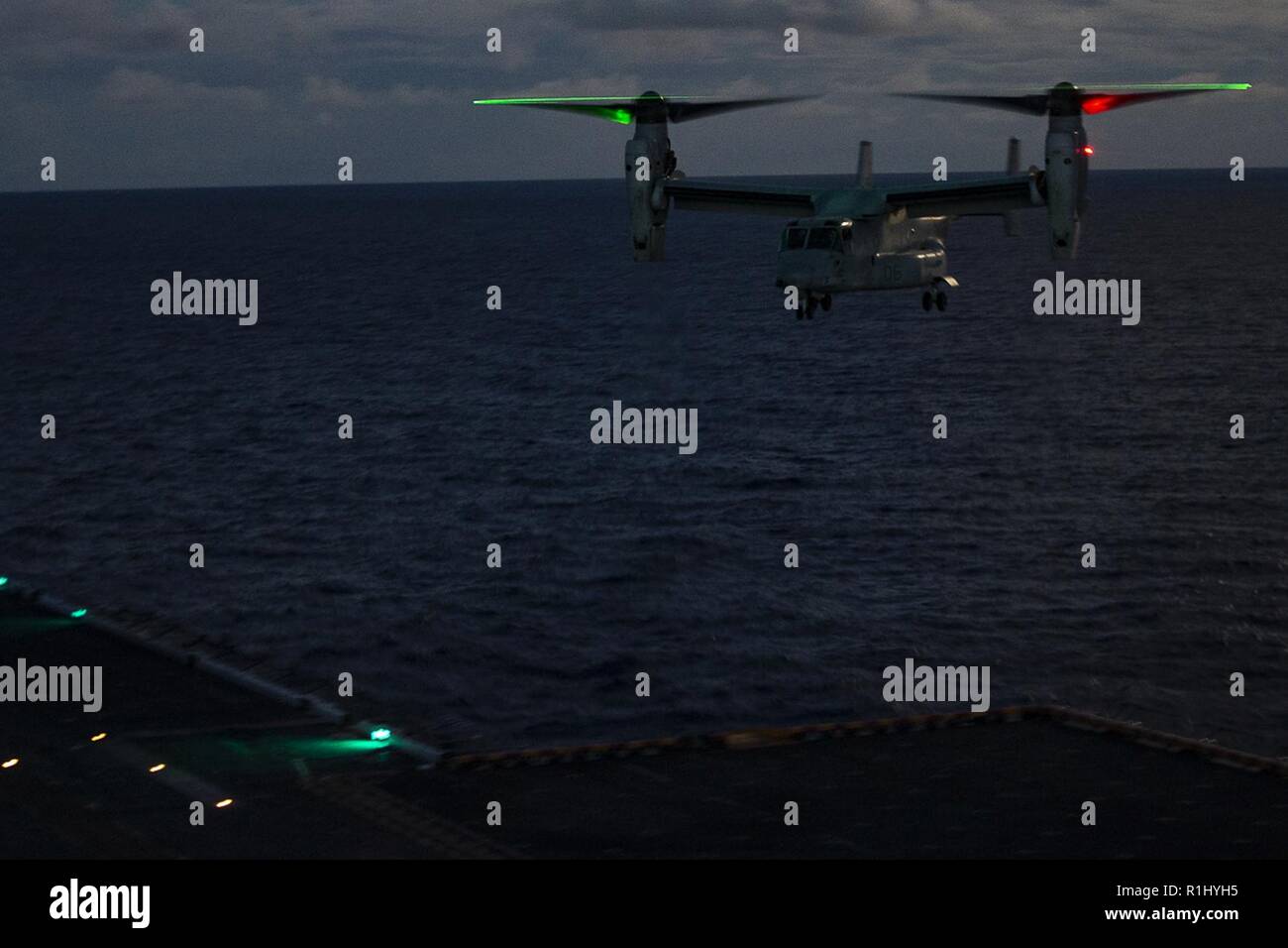 An MV-22B Osprey tiltrotor aircraft prepares to land aboard the amphibious assault ship USS Wasp (LHD 1) during night takeoff and landing training, underway in the East China Sea, Sept. 23, 2018. The Osprey belongs to Marine Medium Tiltrotor Squadron 262 (Reinforced), the Aviation Combat Element for the 31st Marine Expeditionary Unit. Marine naval aviators with VMM-262 (Rein.) perform a wide variety of aviation missions for the 31st MEU, including troop transport, heavy and medium lift, fixed-wing attack support and aerial reconnaissance. The 31st MEU, the Marine Corps’ only continuously forwa Stock Photo