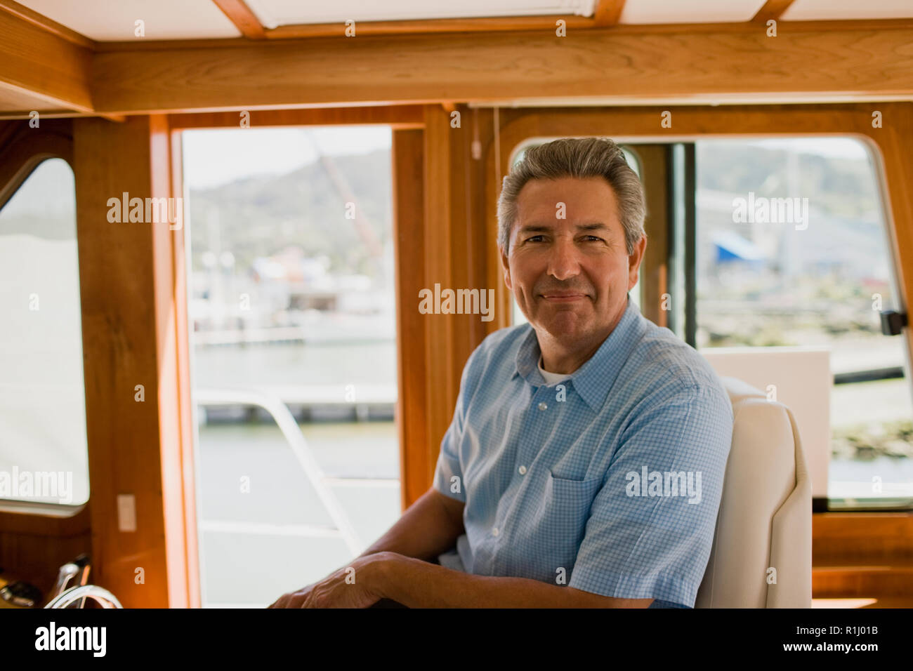 Mature man sitting in a boat looking content Stock Photo - Alamy