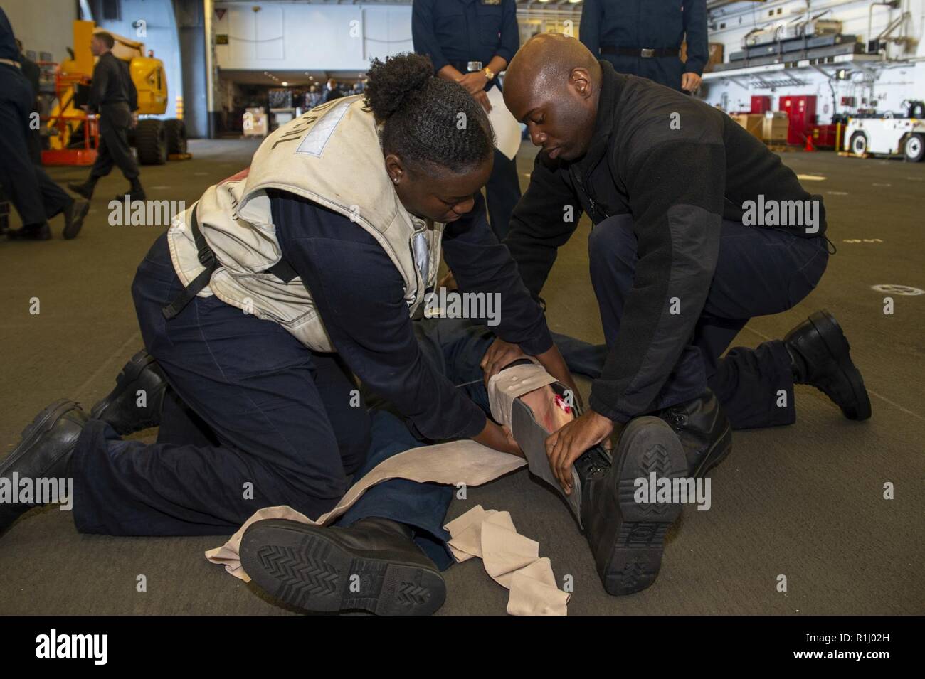 PACIFIC OCEAN (Sept. 21, 2018) Hospital Corpsman 3rd Class Mercy Onwunta, left, from Bronx, N.Y., and Hospital Corpsman 2nd Class Dominique Scott, from Houston, treat a simulated casualty during a mass casualty drill in the hangar bay of the amphibious assault ship USS Bonhomme Richard (LHD 6). Bonhomme Richard is currently underway in the U.S. 3rd Fleet area of operations. Stock Photo