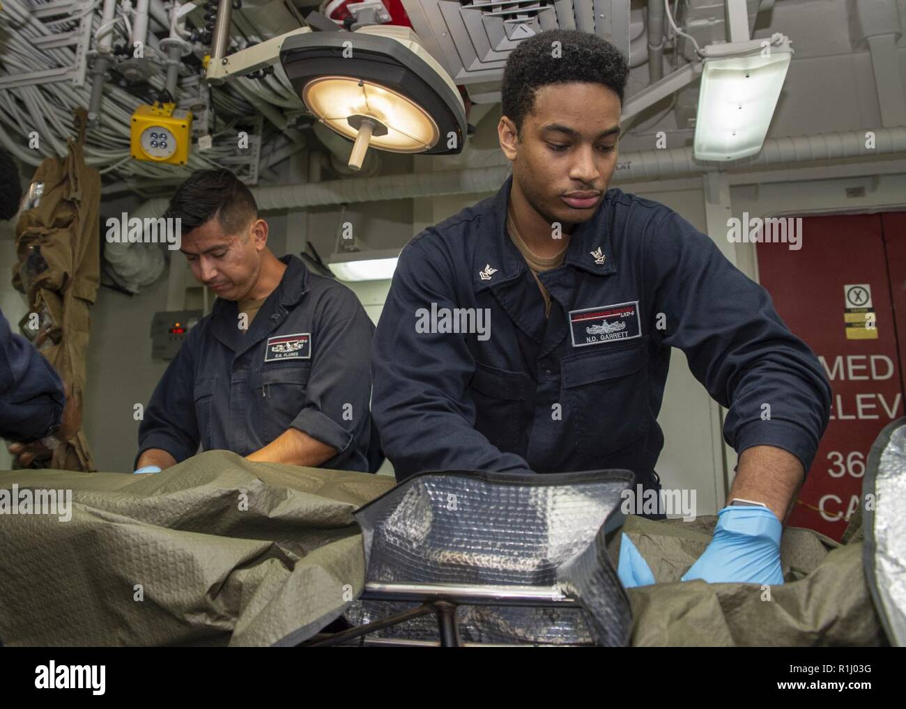 PACIFIC OCEAN (Sept. 21, 2018) Hospital Corpsman 2nd Class Nathaniel Garrett, right, from St. Louis, and Hospitalman Emmanuel Flores, from Chicago, treat a simulated casualty during a mass casualty drill in the medical triage room of the amphibious assault ship USS Bonhomme Richard (LHD 6). Bonhomme Richard is currently underway in the U.S. 3rd Fleet area of operations. Stock Photo