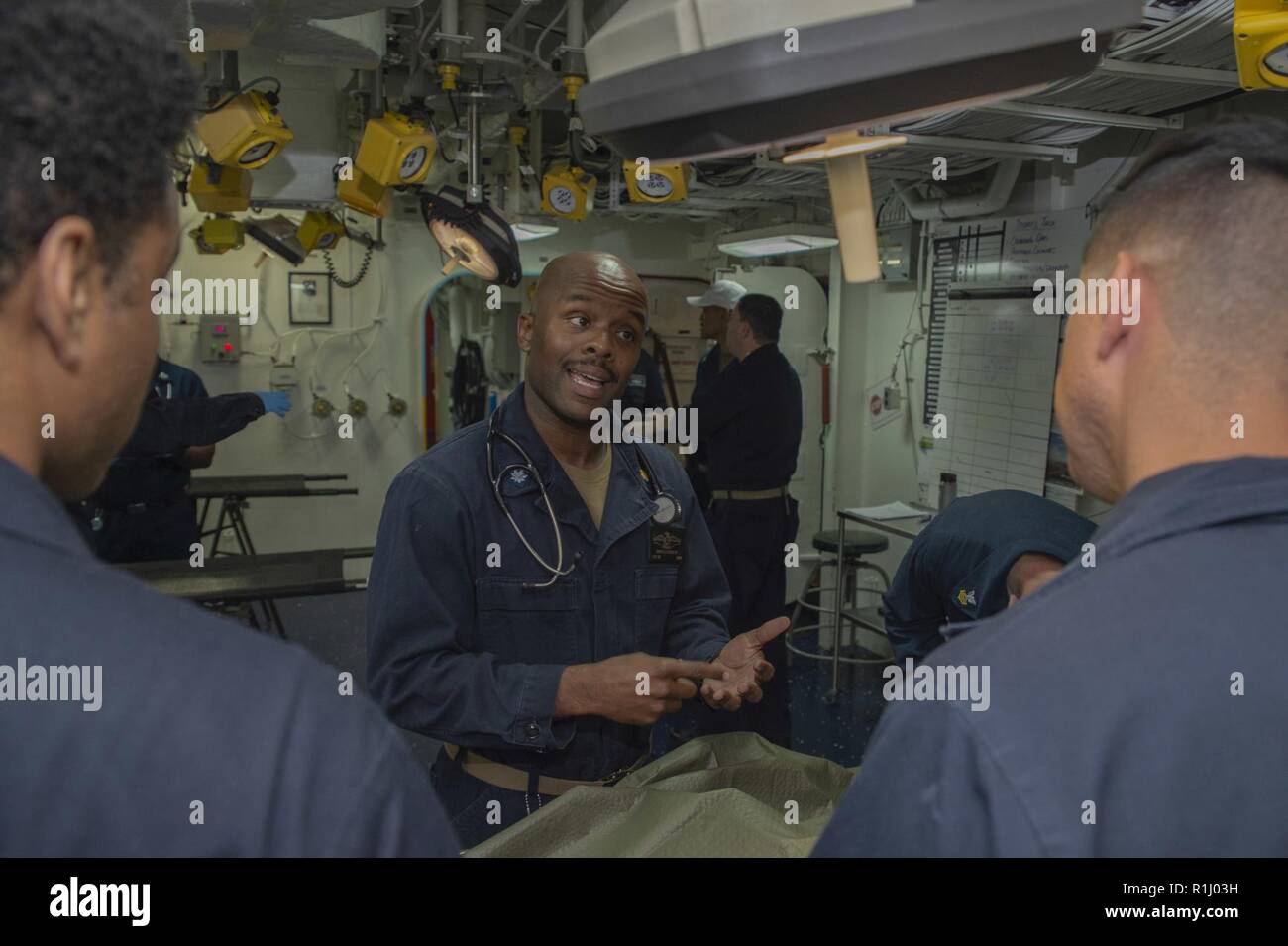 PACIFIC OCEAN (Sept. 21, 2018) Cmdr. Garfield Cross IV, from Annandale, Va., discusses triage procedures with Hospitalman Emmanuel Flores, left, from Chicago, and Hospital Corpsman 2nd Class Nathaniel Garrett, from St. Louis, during a mass casualty drill in the medical triage room of the amphibious assault ship USS Bonhomme Richard (LHD 6). Bonhomme Richard is currently underway in the U.S. 3rd Fleet area of operations. Stock Photo