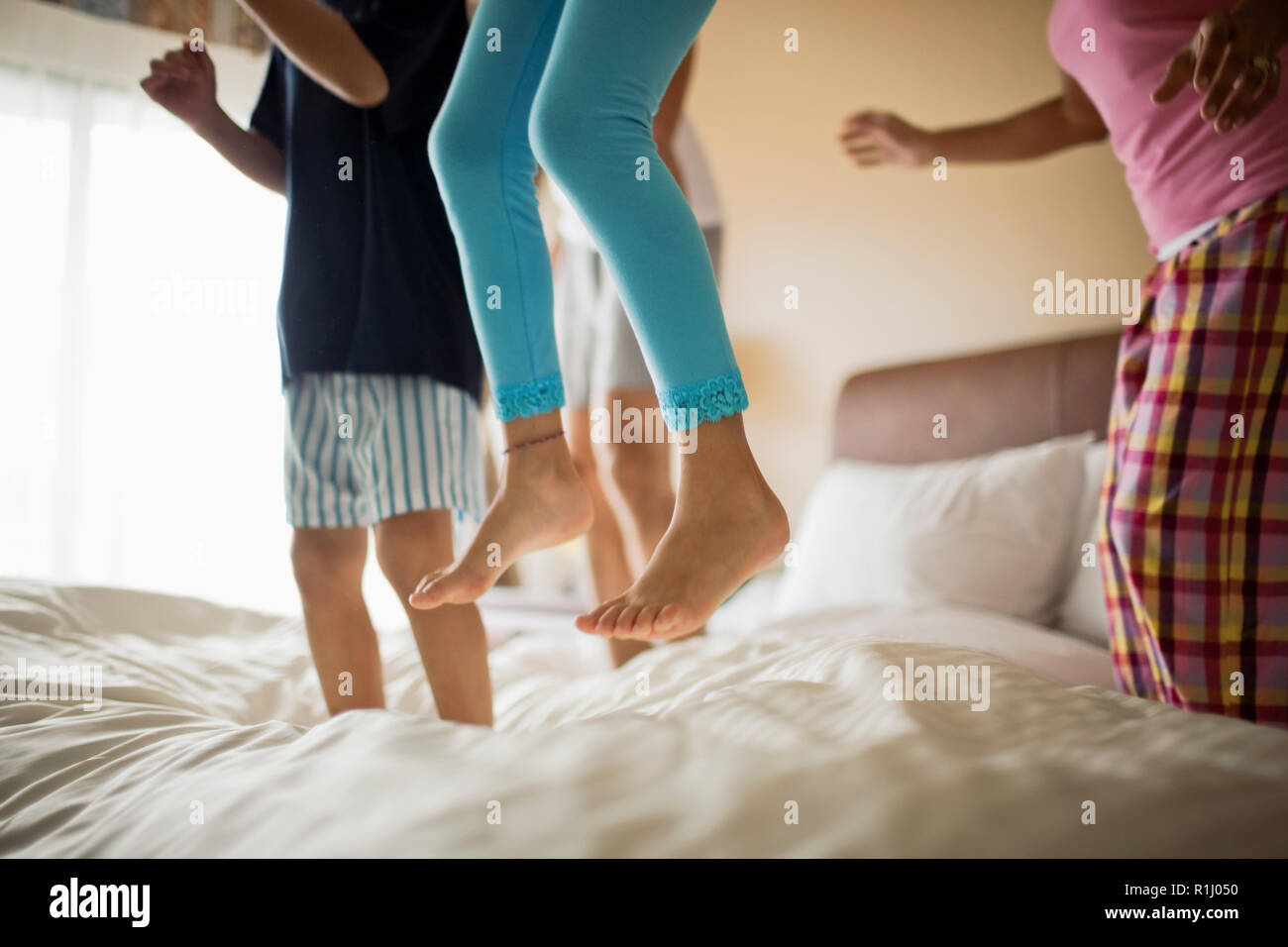 Family jumping on bed together Stock Photo