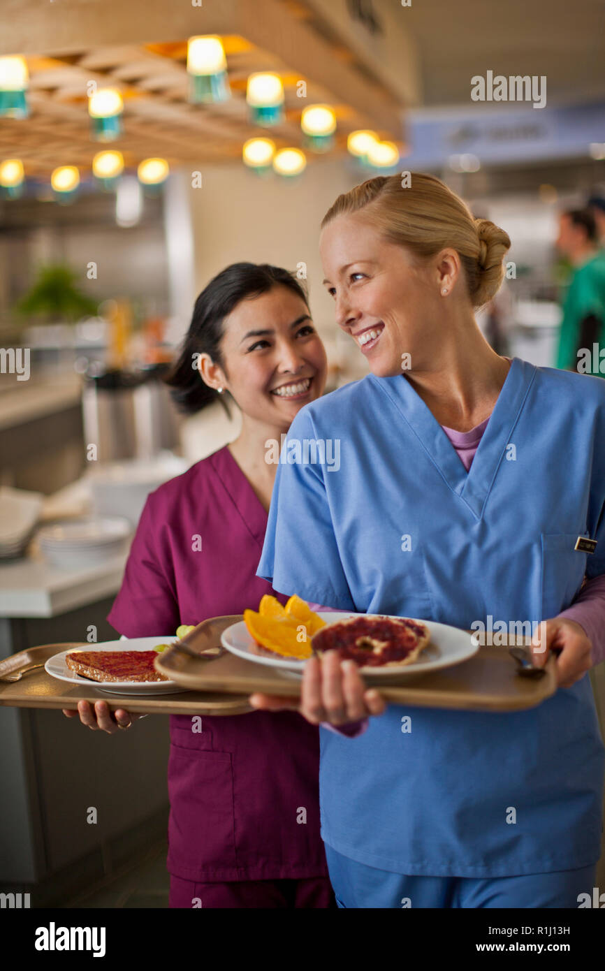 Two young nurses smile and chat together as they get their lunch from