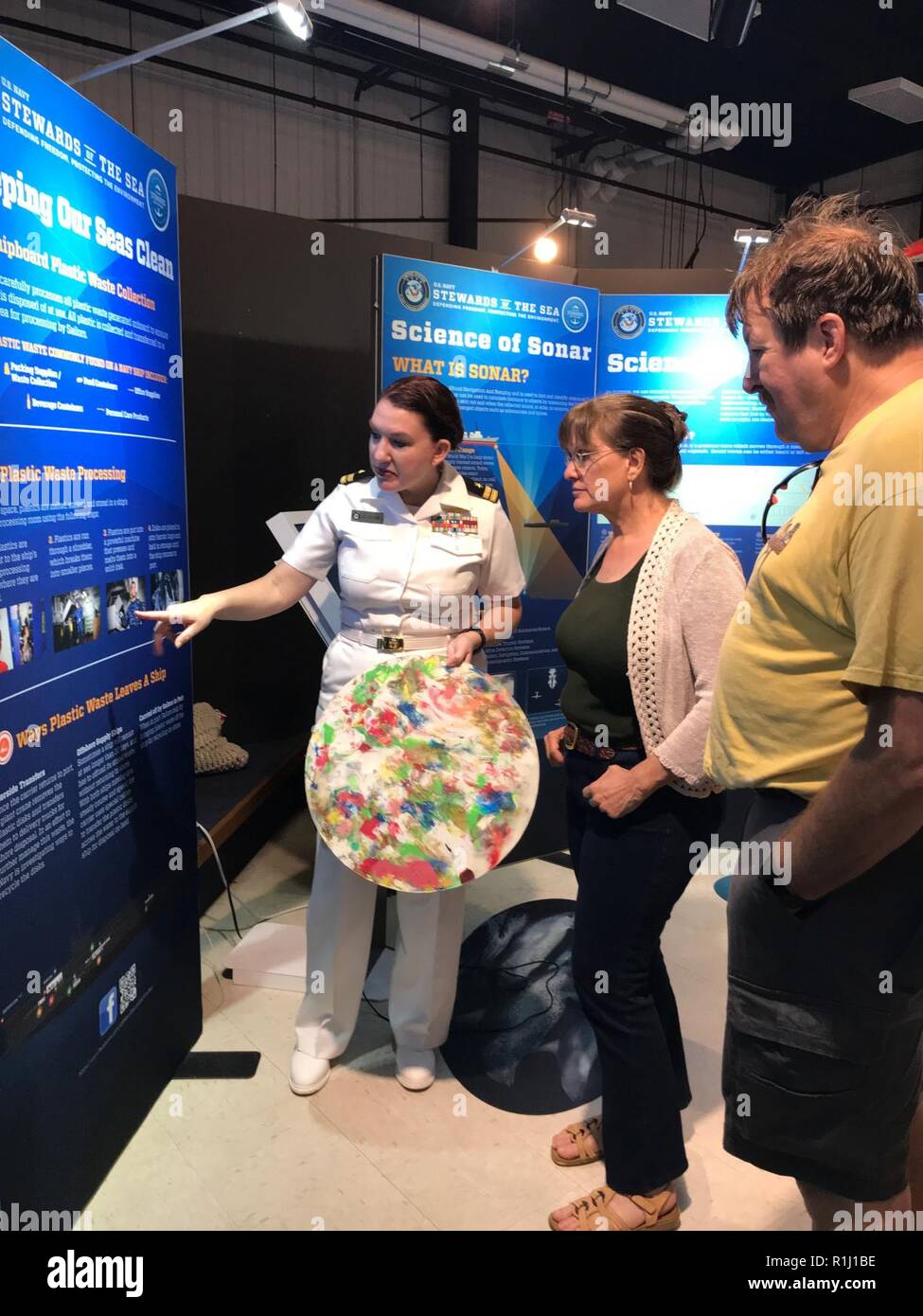 WALLOPS ISLAND, Va. (Sept. 22, 2018) Lt. Jill Brown, a public affairs officer attached to U.S. Fleet Forces Command, explains shipboard plastic waste processing to visitors at the U.S. Navy’s “Stewards of the Sea: Defending Freedom, Protecting the Environment” exhibit during the NASA 60th anniversary celebration held at the NASA Wallops Flight Facility Visitor Center. The Navy employs every means available to mitigate the potential environmental effects of our activities without jeopardizing the safety of our Sailors or impacting our Navy readiness mission. Stock Photo