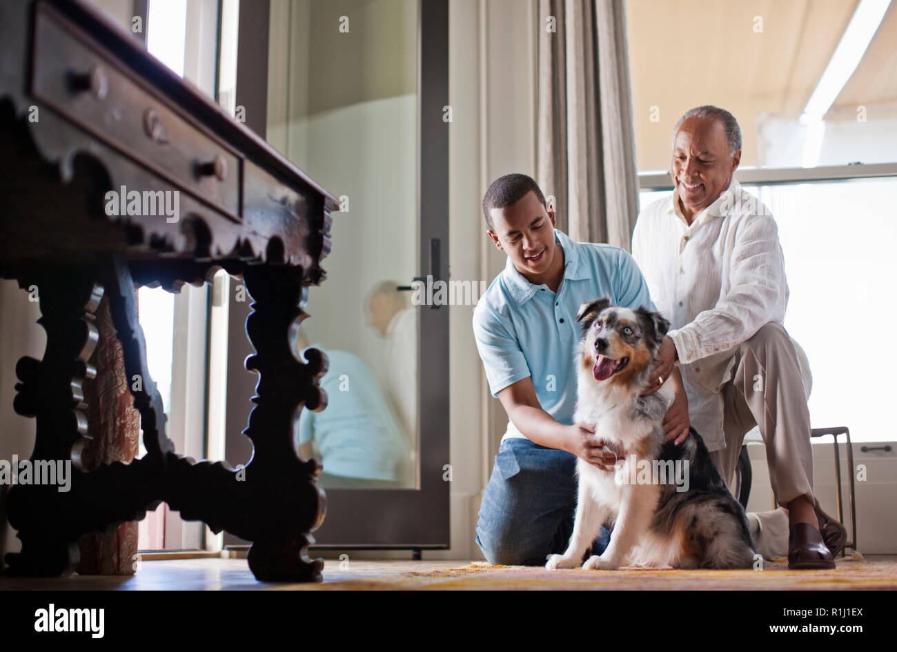 Smiling father and son petting their dog. Stock Photo