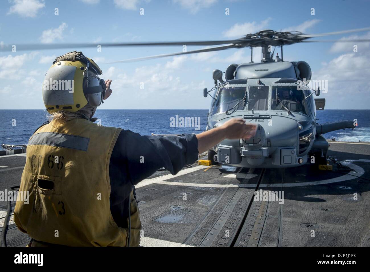 ATLANTIC OCEAN (Sept. 24, 2018) Boatswain's Mate 2nd Class Sarah R. Miller from Manteno, Illinois, directs an MH-60R Sea Hawk helicopter, assigned to the 'Spartans' of Helicopter Maritime Strike Squadron (HSM) 70, during flight operations aboard the Ticonderoga-class guided-missile cruiser USS Hue City (CG 66). Hue City is currently underway on a regularly scheduled deployment. Stock Photo
