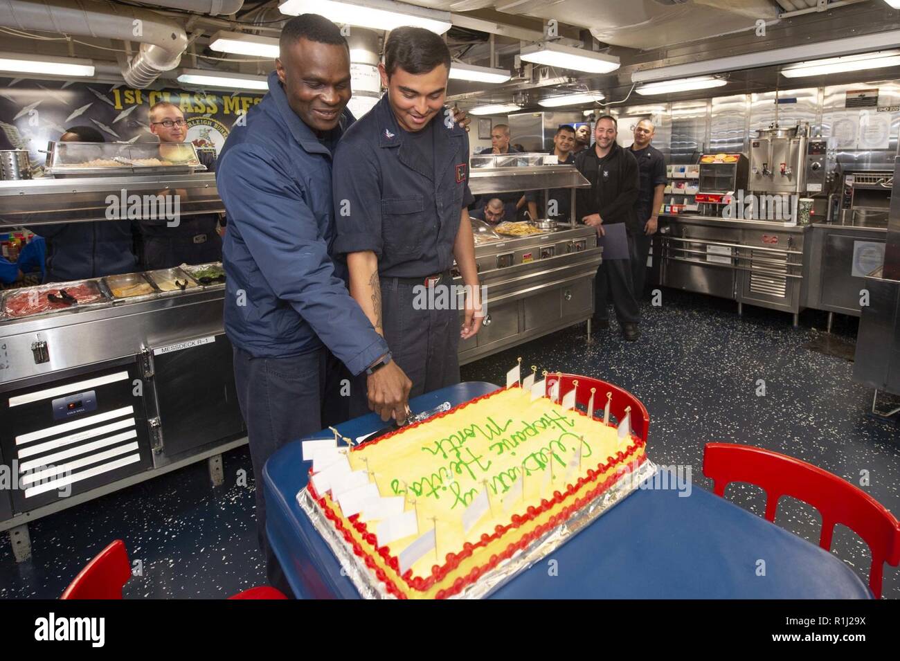 MEDITERRANEAN SEA (Sept. 24, 2018) Cmdr. Errol Robinson, left, commanding officer of the Arleigh Burke-class guided-missile destroyer USS Arleigh Burke (DDG 51), cuts a cake with Fire Controlman 3rd Class Gregory Rivera during a Hispanic Heritage Month observance event on the mess decks Sept. 24, 2018. Arleigh Burke, homeported at Naval Station Norfolk, is conducting naval operations in the U.S. 6th Fleet area of operations in support of U.S. national security interests in Europe and Africa. Stock Photo