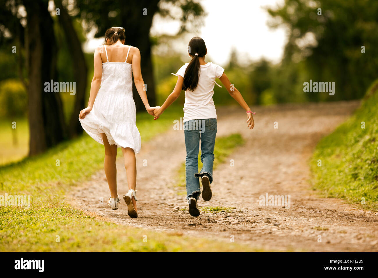 Teenage girl walking hand in hand with her younger sister. Stock Photo