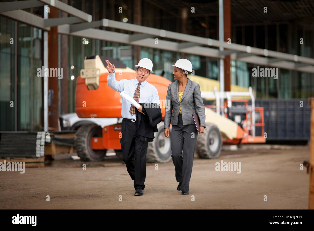 Two smiling engineers discussing plans on a construction site. Stock Photo