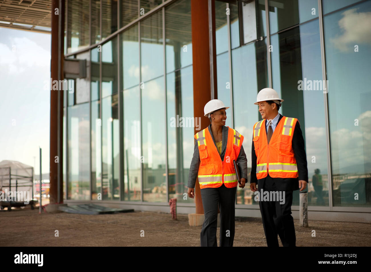 Two smiling engineers discussing plans on a construction site. Stock Photo