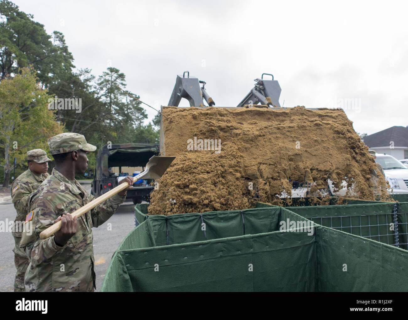 U.S. Army Spc. John Livingston, an equipment operator with the 1227th Engineer Detachment, South Carolina National Guard, fills a HESCO barrier with sand to keep water away from the Tidelands Georgetown Memorial Hospital in Georgetown, South Carolina Sept. 25, 2018. Guardsmen from Batesburg, South Carolina were activated Sept. 11, 2018, in support of partnered civilian agencies to safeguard the citizens of the state during Hurricane Florence and its aftermath. Stock Photo