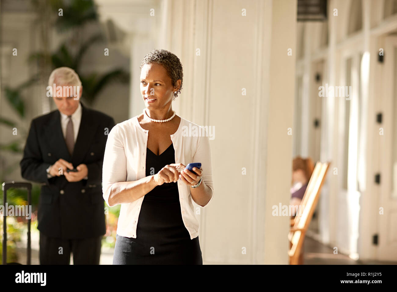 Two business colleagues walking while using cell phone. Stock Photo