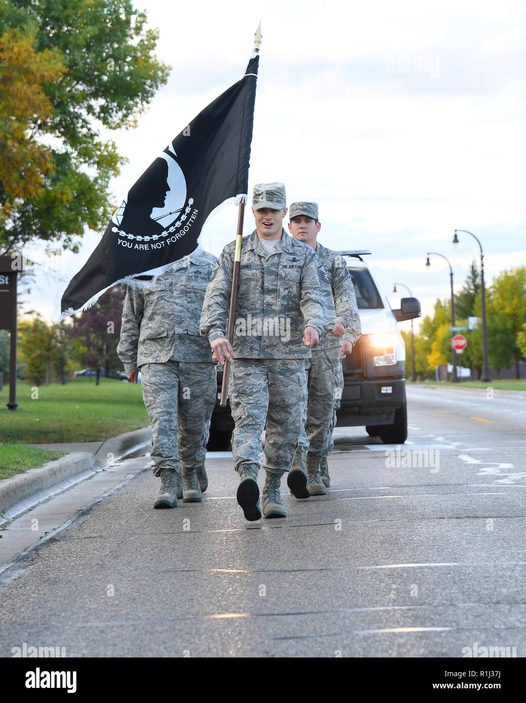 Master Sgt. Daniel Cable, 319th Operations Support Squadron fire sergeant, center, calls cadence as he leads an element to the base honor guard building for a POW/MIA ceremony September 21, 2018, on Grand Forks Air Force Base, North Dakota. Prior to the ceremony, the POW/MIA flag was kept in motion by base Airmen who carried it during a 24-hour run. Stock Photo