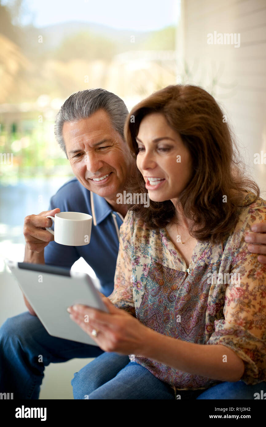 Couple looking at an ipad on their verandah. Stock Photo