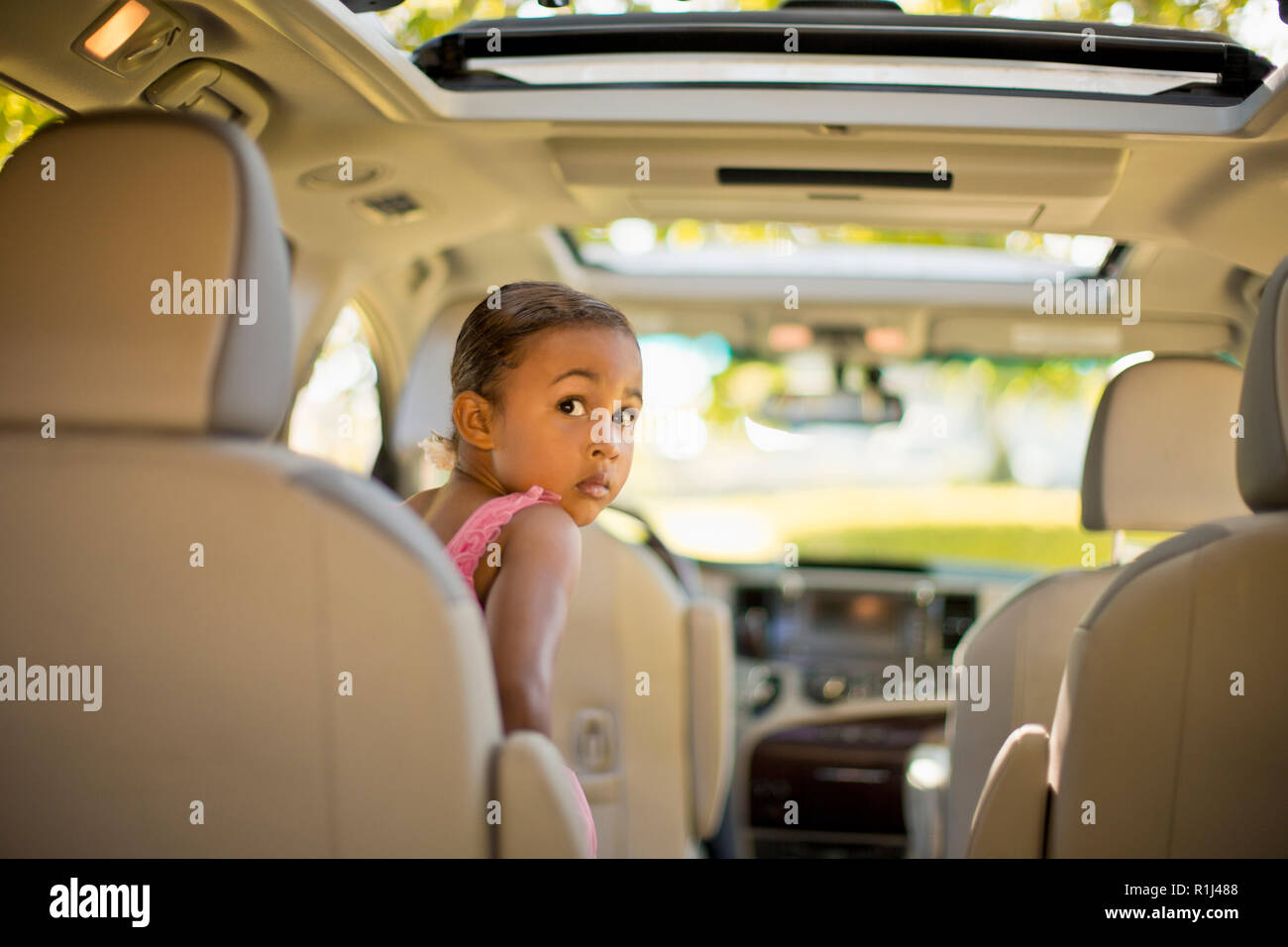 Young girl dressed as a ballerina pretending to drive a car. Stock Photo