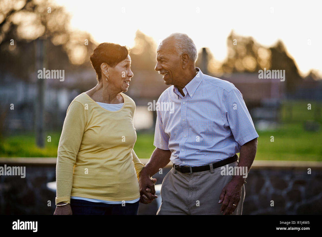 Happy senior couple holding hands while walking in the back yard together. Stock Photo
