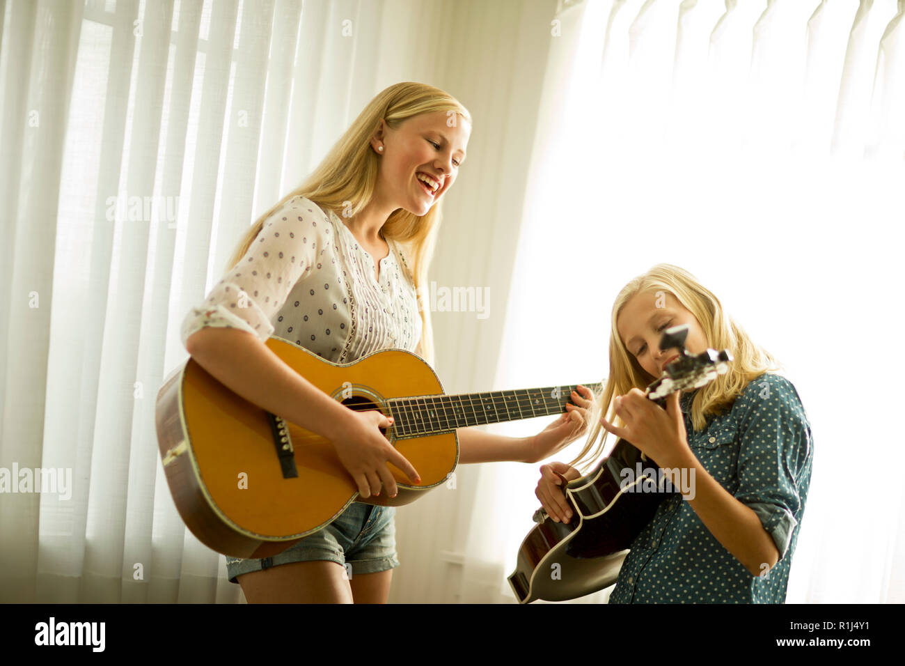 Happy teenage girls playing guitar together. Stock Photo