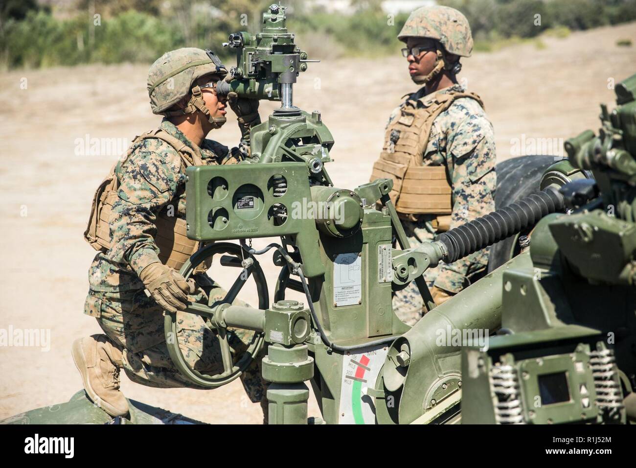 U.S Marine Corps Cpl. Jorge Jimenez (left), field artillery cannoneer, India Battery, 3rd Battalion, 11th Marine Regiment, 1st Marine Division, looks through the sighting system of an M777 155mm Howitzer cannon during a Cannon Section Chief Course at Artillery Fire Area 18, Marine Corps Base Camp Pendleton, California, Sept. 27, 2018. The section chief is responsible for the safety of each Marine operating the Howitzer along with the training and proficiency of the section. Stock Photo