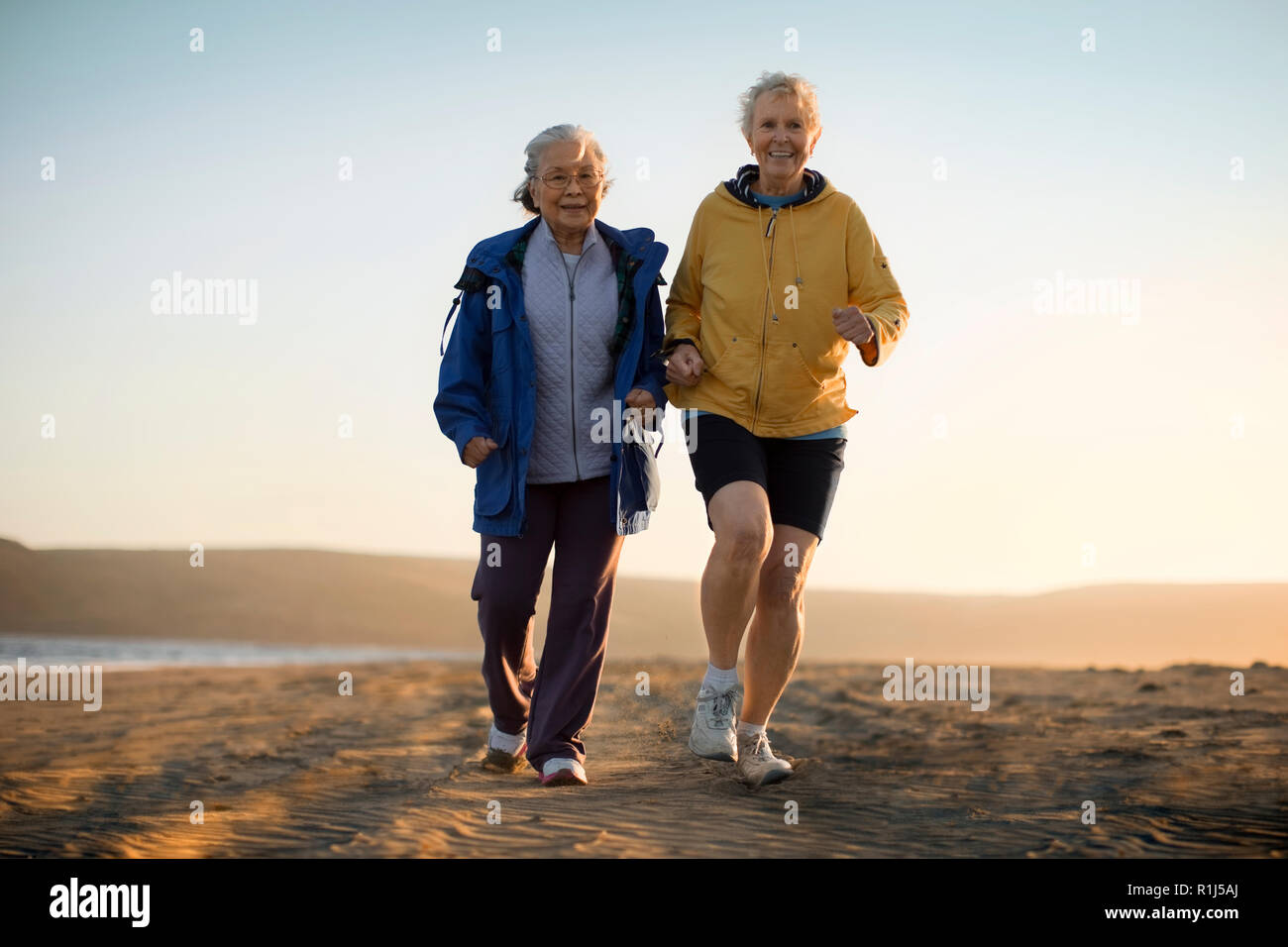 Two senior woman exercising together on the beach. Stock Photo