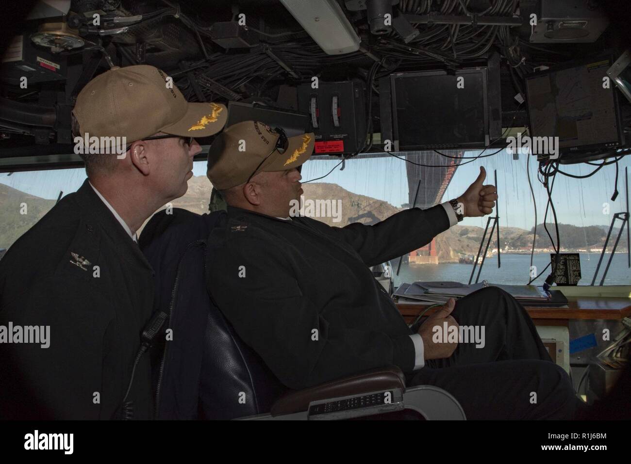 SAN FRANCISCO (Oct. 5, 2018) Capt. Rich LeBron, right, commanding officer of the amphibious assault ship USS Bonhomme Richard (LHD 6), and Gregory Thoroman, the ship’s executive officer, navigate the ship under the Golden Gate Bridge while participating in the Parade of Ships as part of San Francisco Fleet Week 2018. San Francisco Fleet Week is an opportunity for the American public to meet their Navy, Marine Corps and Coast Guard teams and experience America’s sea services. During fleet week, service members participate in various community service events, showcase capabilities and equipment  Stock Photo