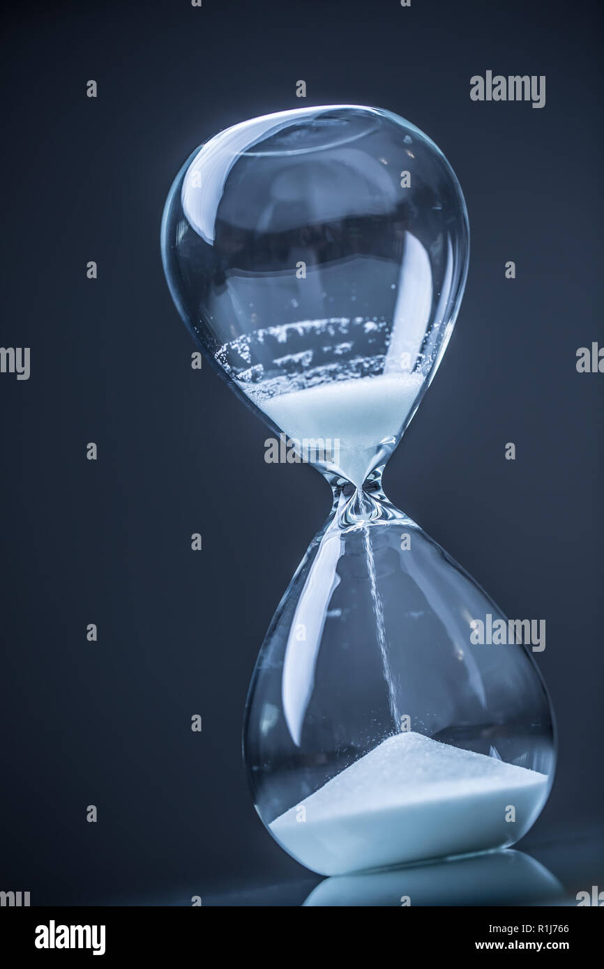 Modern hourglass in running time in studio lights Stock Photo - Alamy