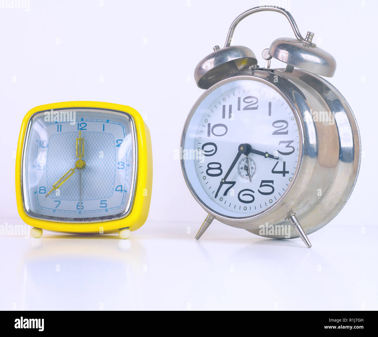 Two vintage alarm clocks isolated on white background Stock Photo - Alamy