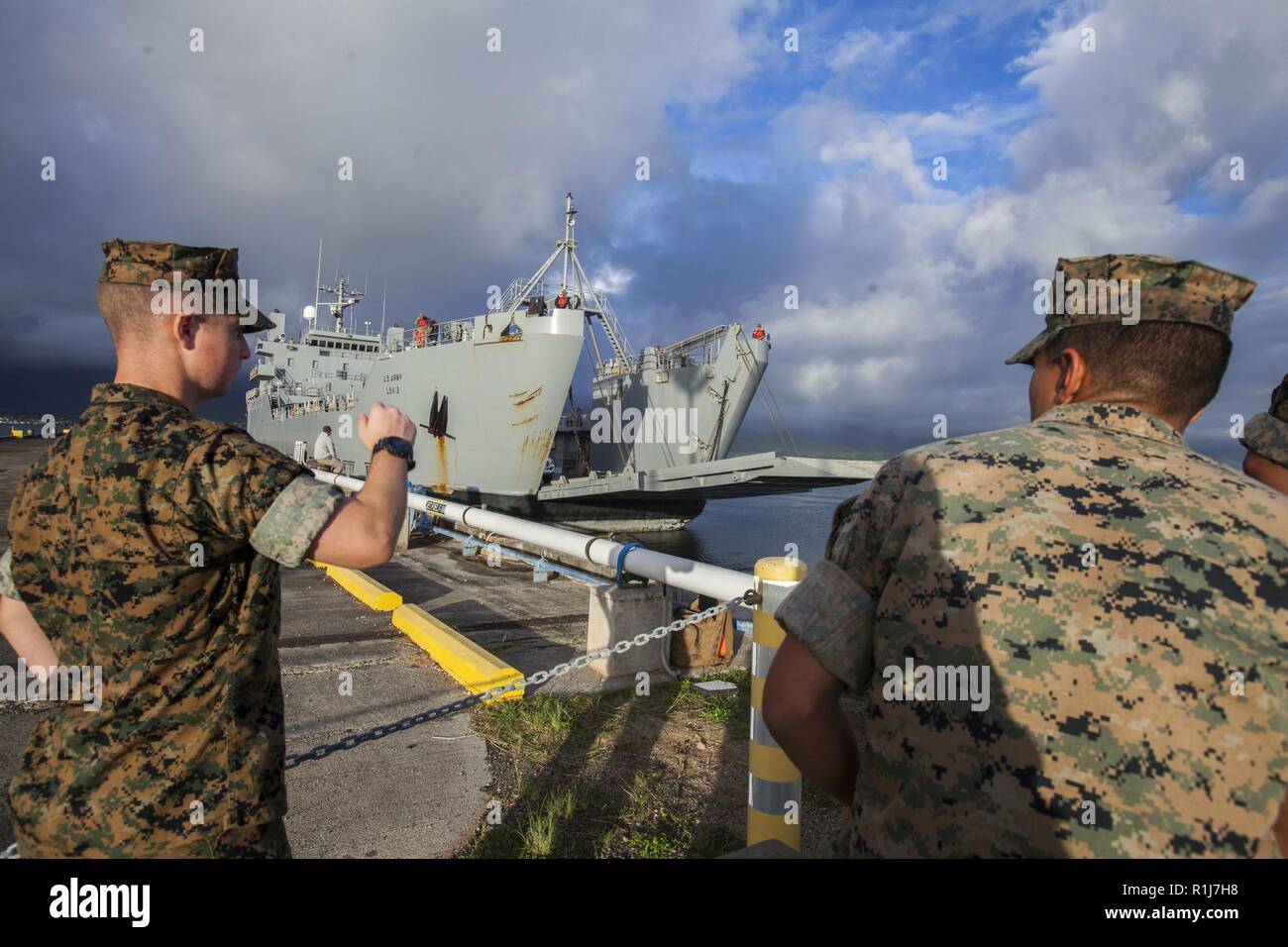 U.S. Marines watch a Logistics Support Vessel pull into the Marina ...