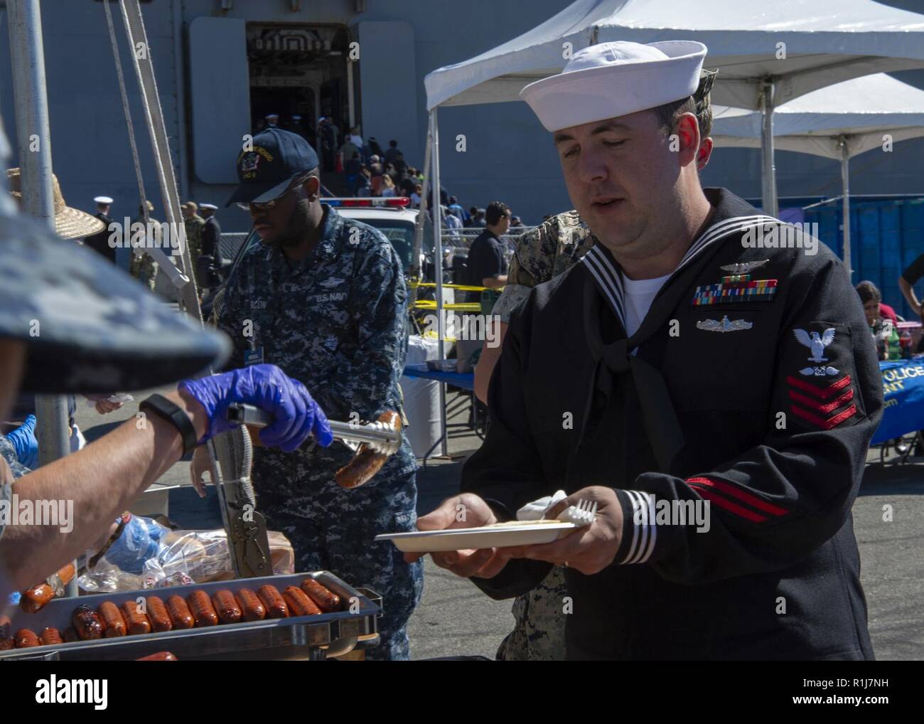 SAN FRANCISCO (Oct. 7, 2018) A member of the Navy League of Oakland serves a meal to Aviation Boatswain’s Mate (Fuel) 1st Class Timothy Giffin, from Reno, Nev., assigned to the amphibious assault ship USS Bonhomme Richard (LHD 6), during a barbeque for the crew event during San Francisco Fleet Week 2018. San Francisco Fleet Week is an opportunity for the American public to meet their Navy, Marine Corps and Coast Guard teams and experience America’s sea services. During fleet week, service members participate in various community service events, showcase capabilities and equipment to the commun Stock Photo