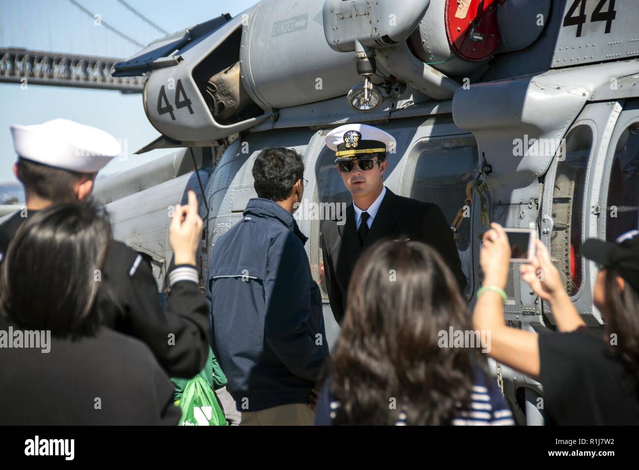 SAN FRANCISCO (Oct. 7, 2018) Lt. Scott Stamer, from San Diego, assigned to the Helicopter Sea Combat Squadron (HSC) 23, describes the capabilities of an MH-60S Sea Hawk helicopter to visitors during a general public tour of the amphibious assault ship USS Bonhomme Richard (LHD 6) during San Francisco Fleet Week 2018. San Francisco Fleet Week is an opportunity for the American public to meet their Navy, Marine Corps, and Coast Guard teams and experience America’s sea services. During Fleet Week, service members participate in various community service events, showcase capabilities and equipment Stock Photo