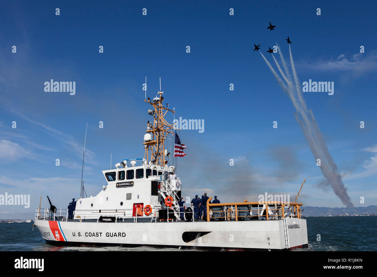The USCG cutter 'Hawksbill' (WPB-87312) patrols San Francisco Bay as the Blue Angels do a formation break above. Stock Photo