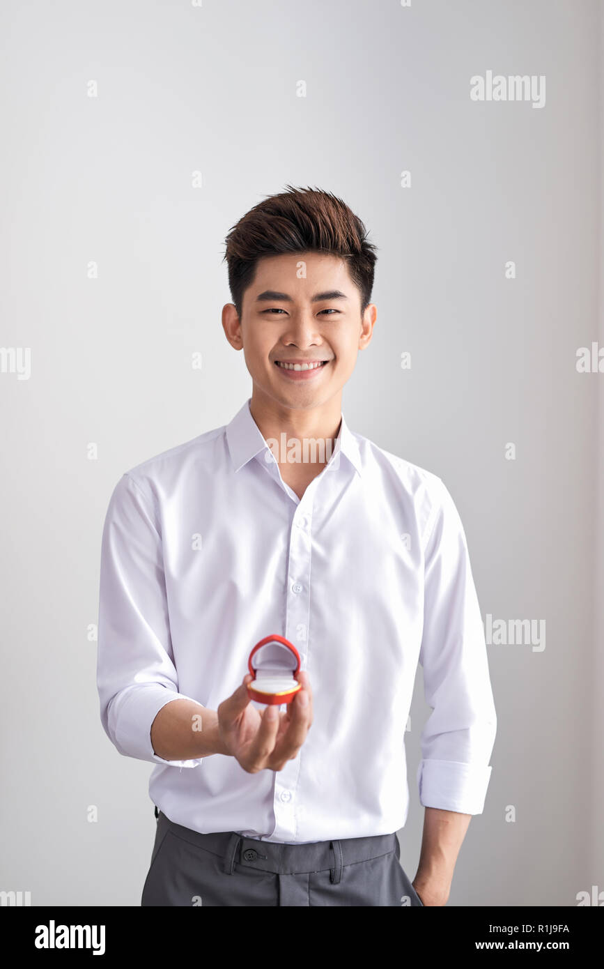 Handsome elegant man in a white shirt is holding a box with an engagement ring and shows in camera. Stock Photo