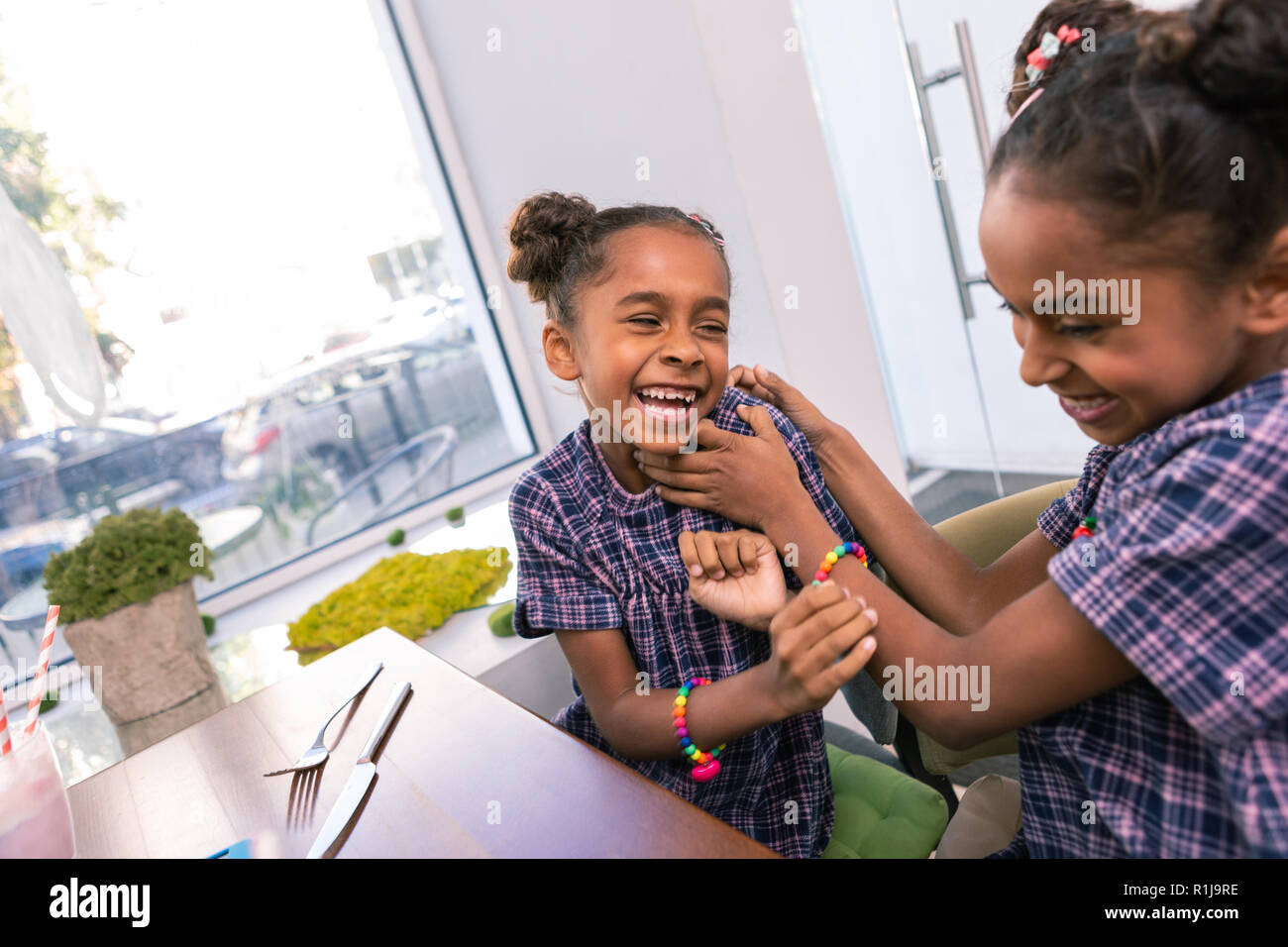 Curly siblings playing tricks while waiting for dinner in restaurant Stock Photo