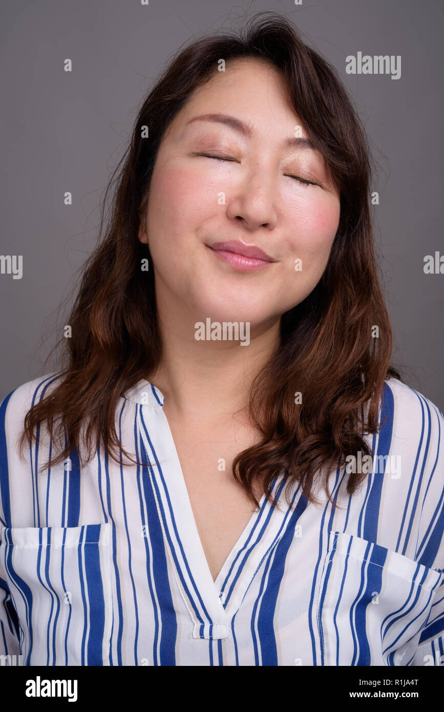 Face of mature beautiful Asian woman with eyes closed Stock Photo