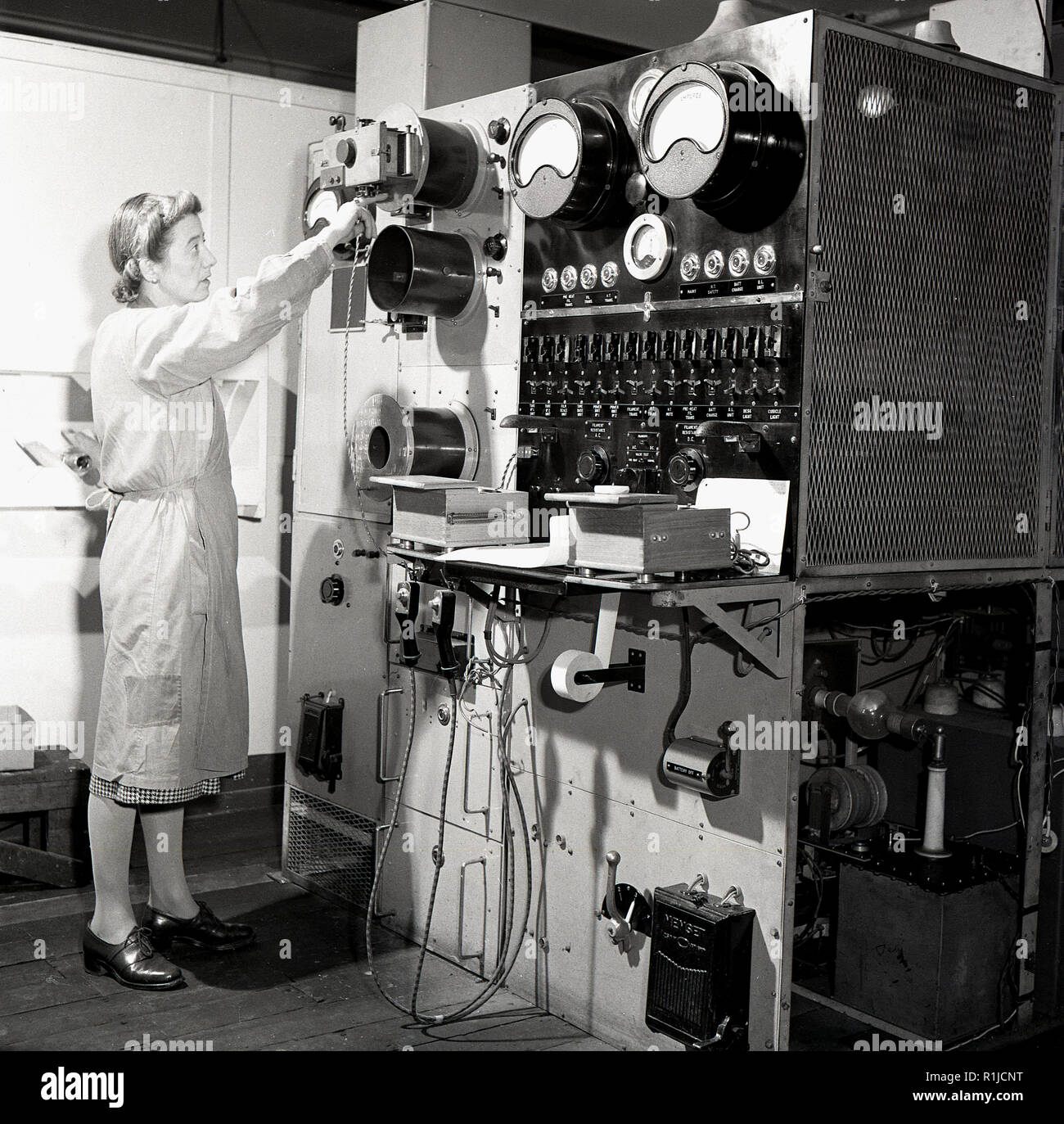 1950s, historical, a female worker using equipment with ampere meters, electrical instruments that measure electric currents. An ampere or amp is a unit of electrical current and an Ampere is named after Frenchman Andre-Maries Ampere. Stock Photo