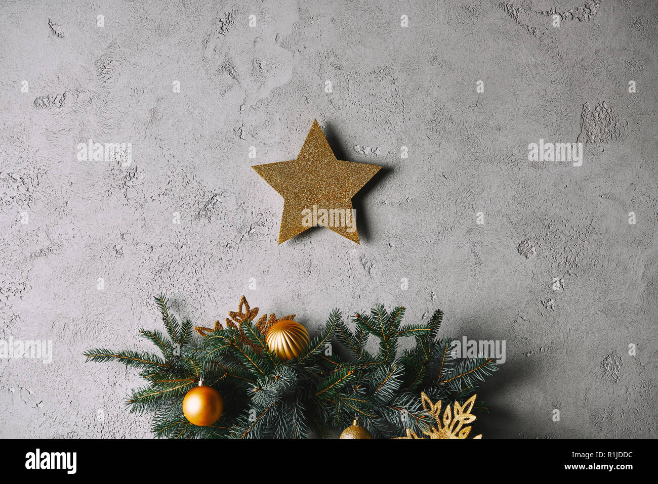 Christmas golden star hanging on grey wall above christmas tree in room ...