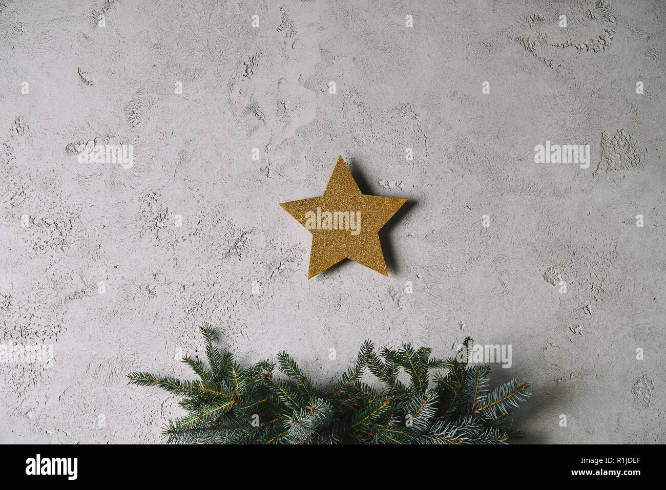 Christmas golden star hanging on grey wall above christmas tree in room ...