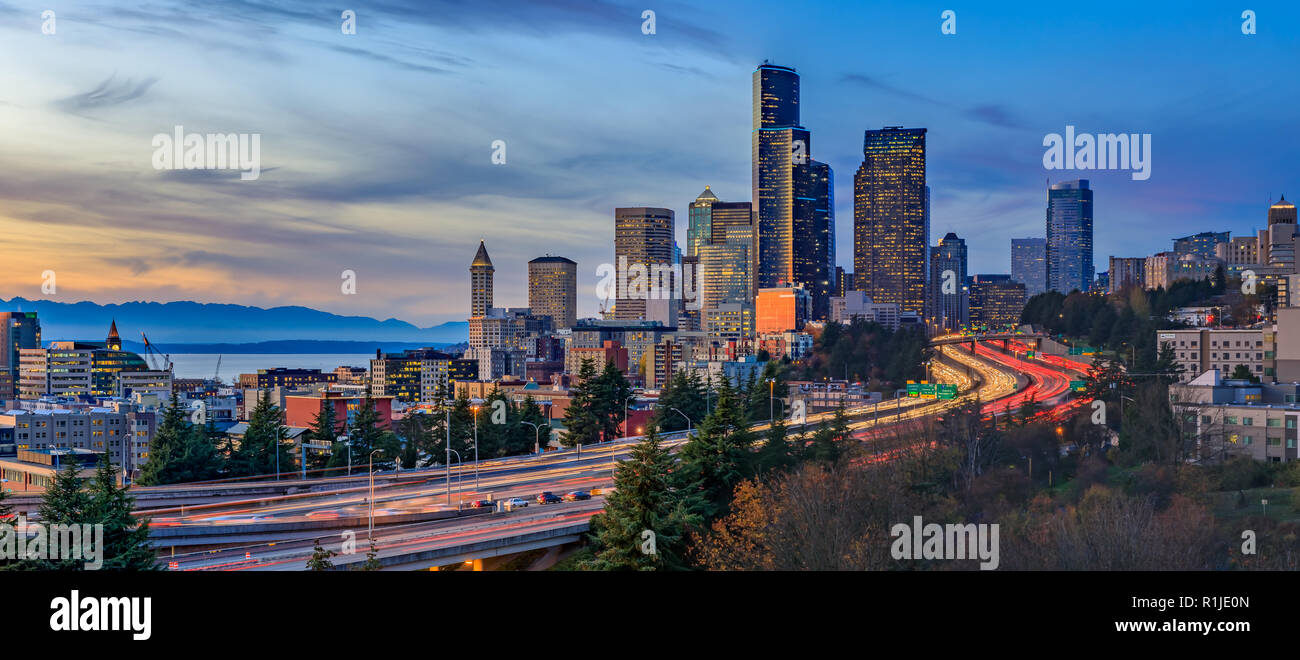 Panorama of Seattle downtown skyline beyond the I-5 I-90 freeway interchange at sunset with long exposure traffic trail lights from Dr. Jose Rizal or  Stock Photo