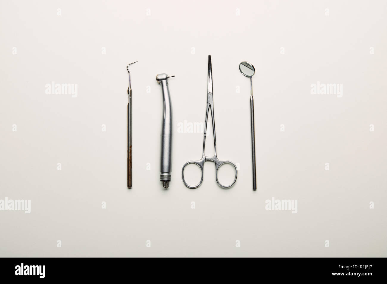 flat lay with stainless dental instruments arranged on white tabletop ...