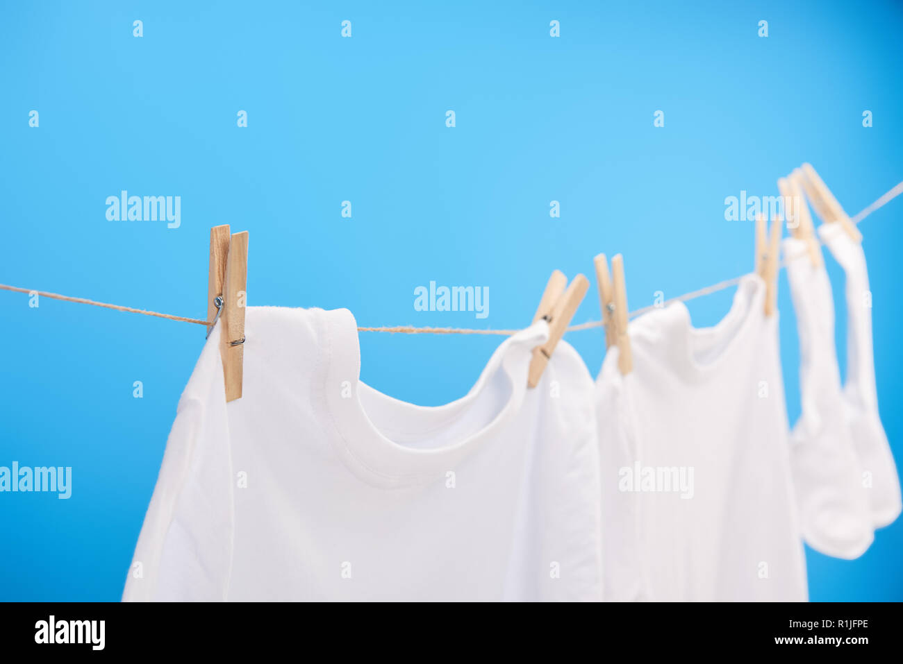 close-up view of clean white t-shirts and socks hanging on clothesline isolated on blue Stock Photo